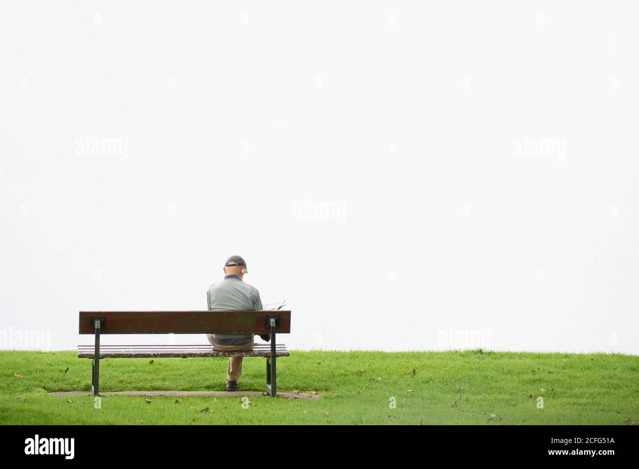 Soziale Distanzierung einzelner Mann allein auf Sitz im Freien Stockfoto