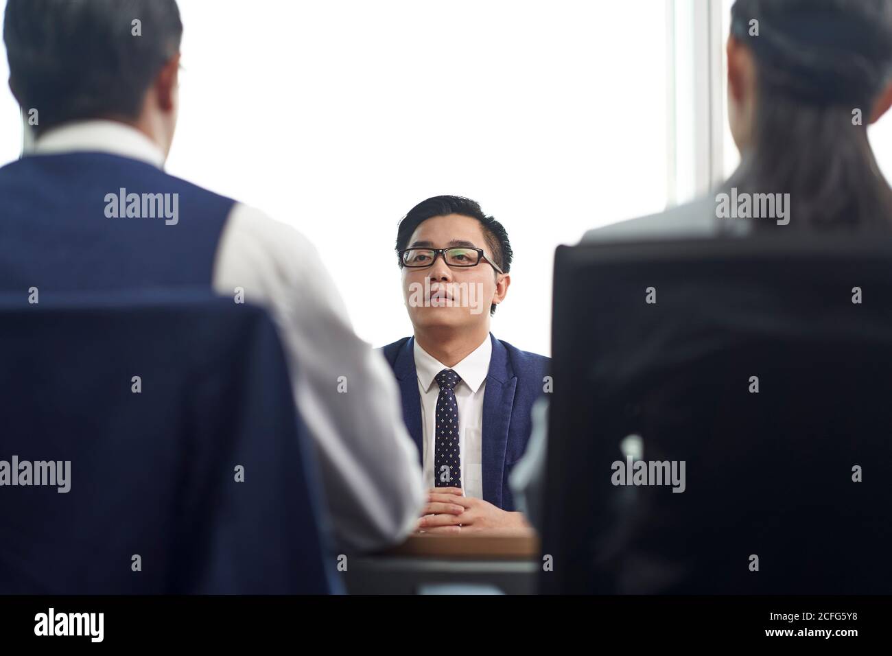 Junger asiatischer Geschäftsmann, der von zwei HR-Führungskräften interviewt wird Im Büro Stockfoto