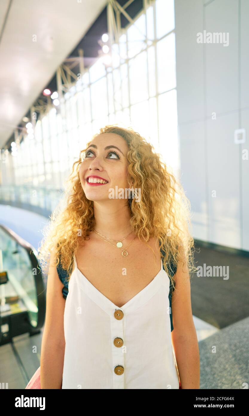 Lockige Frau mit Rucksack, die in der hellen Flughafenhalle in Texas läuft Stockfoto