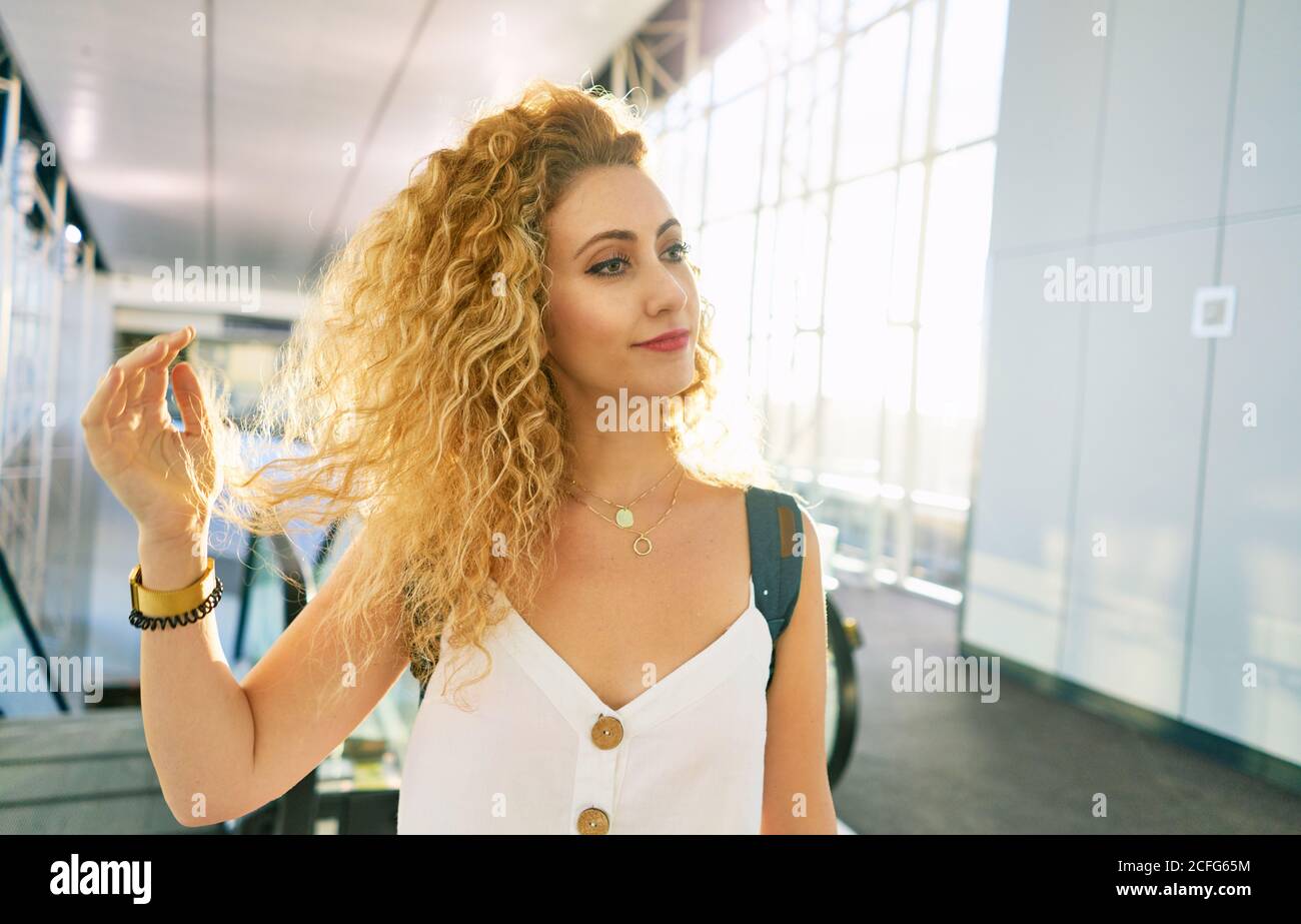 Lockige Frau mit Rucksack, die in der hellen Flughafenhalle in Texas läuft Stockfoto