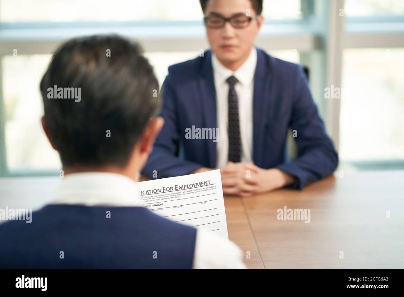 asiatischer HR-Manager, der sich während eines Vorstellungsgesprächs mit der Bewerbung um eine Beschäftigung beschäftigt, konzentriert sich auf das Dokument Stockfoto