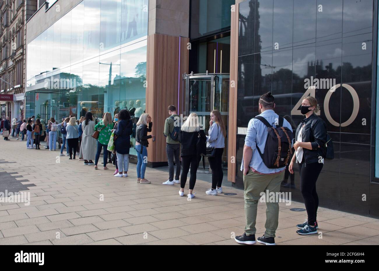 Edinburgh, Schottland, Großbritannien. September 2020. Princes Street Geschäfte lange gesellschaftlich distanzierte Warteschlangen vor den Geschäften am Samstagnachmittag. Im Bild stehen junge Leute vor H&M. Quelle: Arch White/ Alamy Live News. Stockfoto