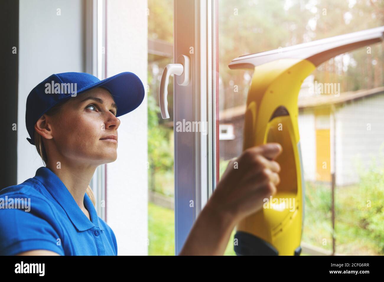 Home Reinigungsservice - Frau Waschfenster mit Staubsauger Stockfoto