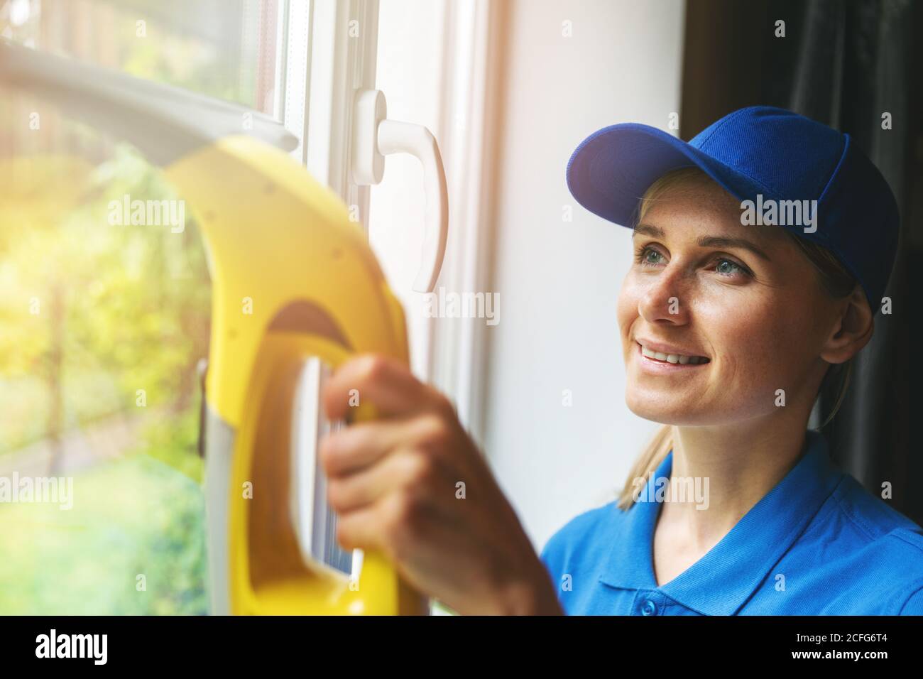 Home Reinigungsservice - Frau Waschfenster mit Staubsauger Stockfoto