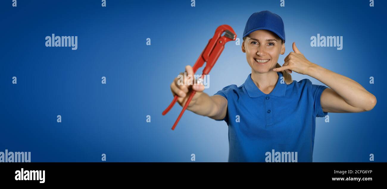 Sanitär - Frau Klempner mit Schraubenschlüssel zeigt Anruf Geste auf blauem Hintergrund mit Kopierplatz Stockfoto