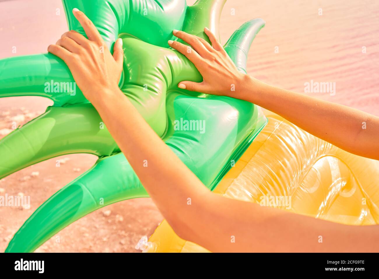 Crop-Ansicht der bronzed Frau berühren helle Ananas aufblasbare Matratze am Strand in der roten Lagune Stockfoto