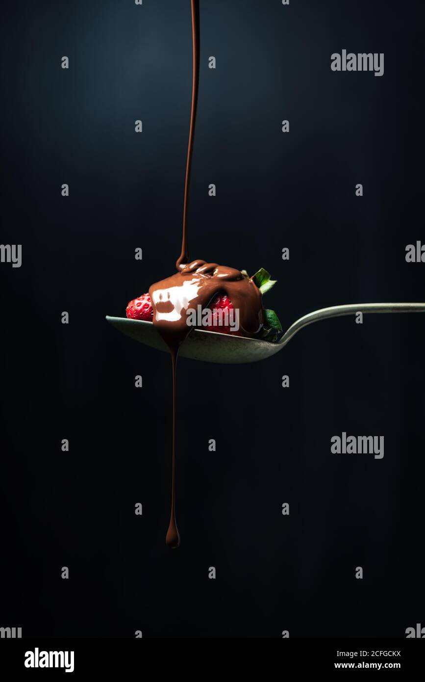Köstliche Schokolade Ganache Jet von Schokolade fallen auf Eine Erdbeere auf einem Löffel Stockfoto