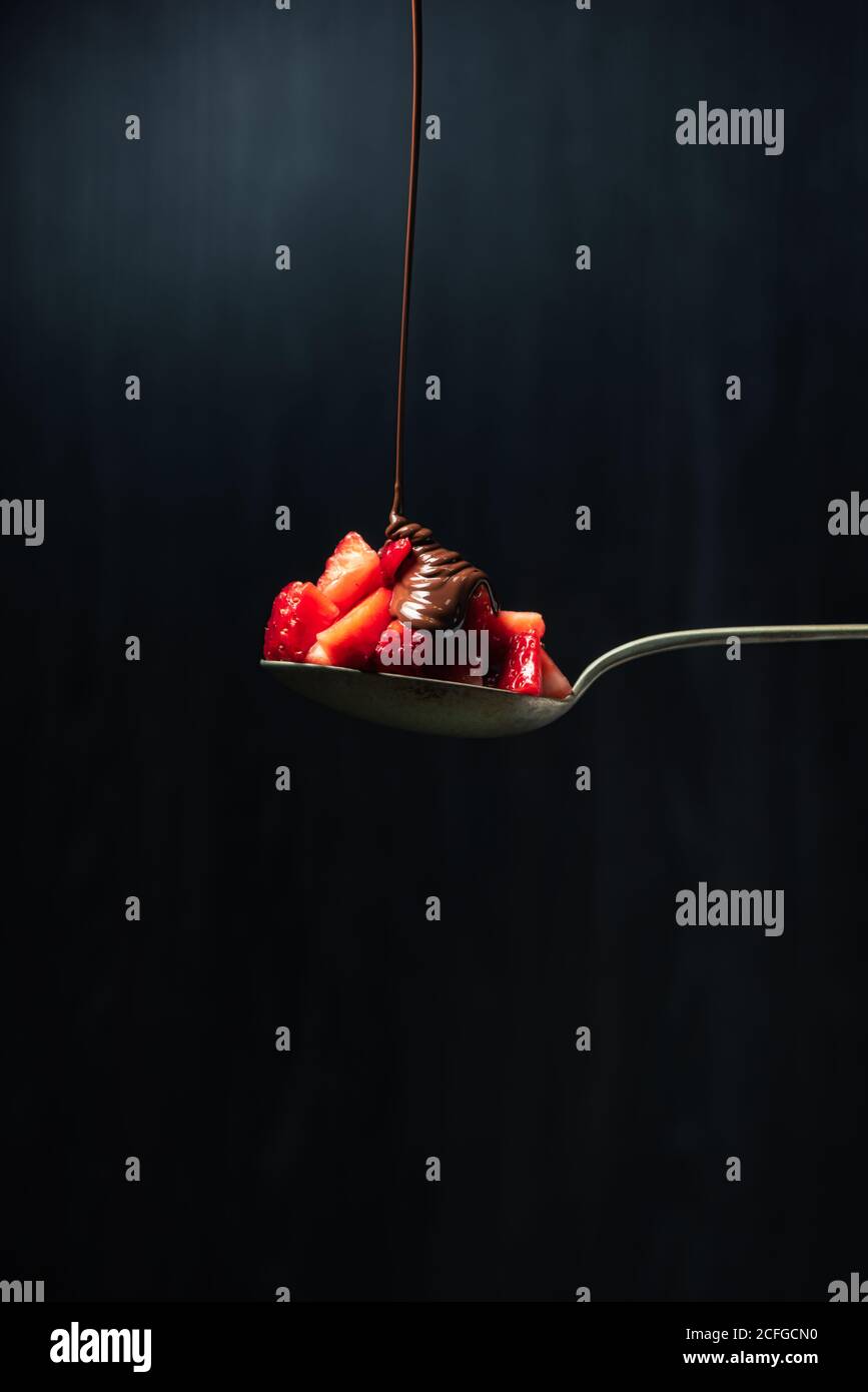 Köstliche Schokolade Ganache Jet von Schokolade fallen auf Eine Erdbeere auf einem Löffel Stockfoto