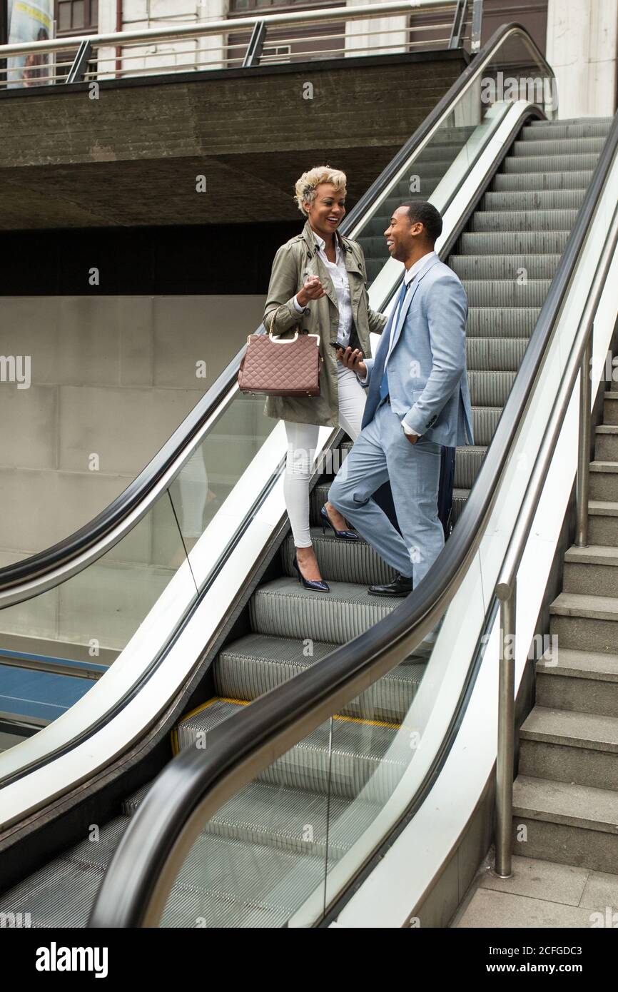 Fröhlicher, trendiger Mann und Frau auf der Treppe, die pendeln und sich freundlich unterhalten. Stockfoto