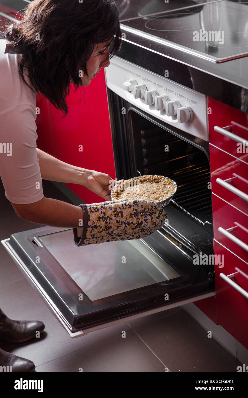 Frau, die einen Kuchen in den Ofen legt Stockfoto