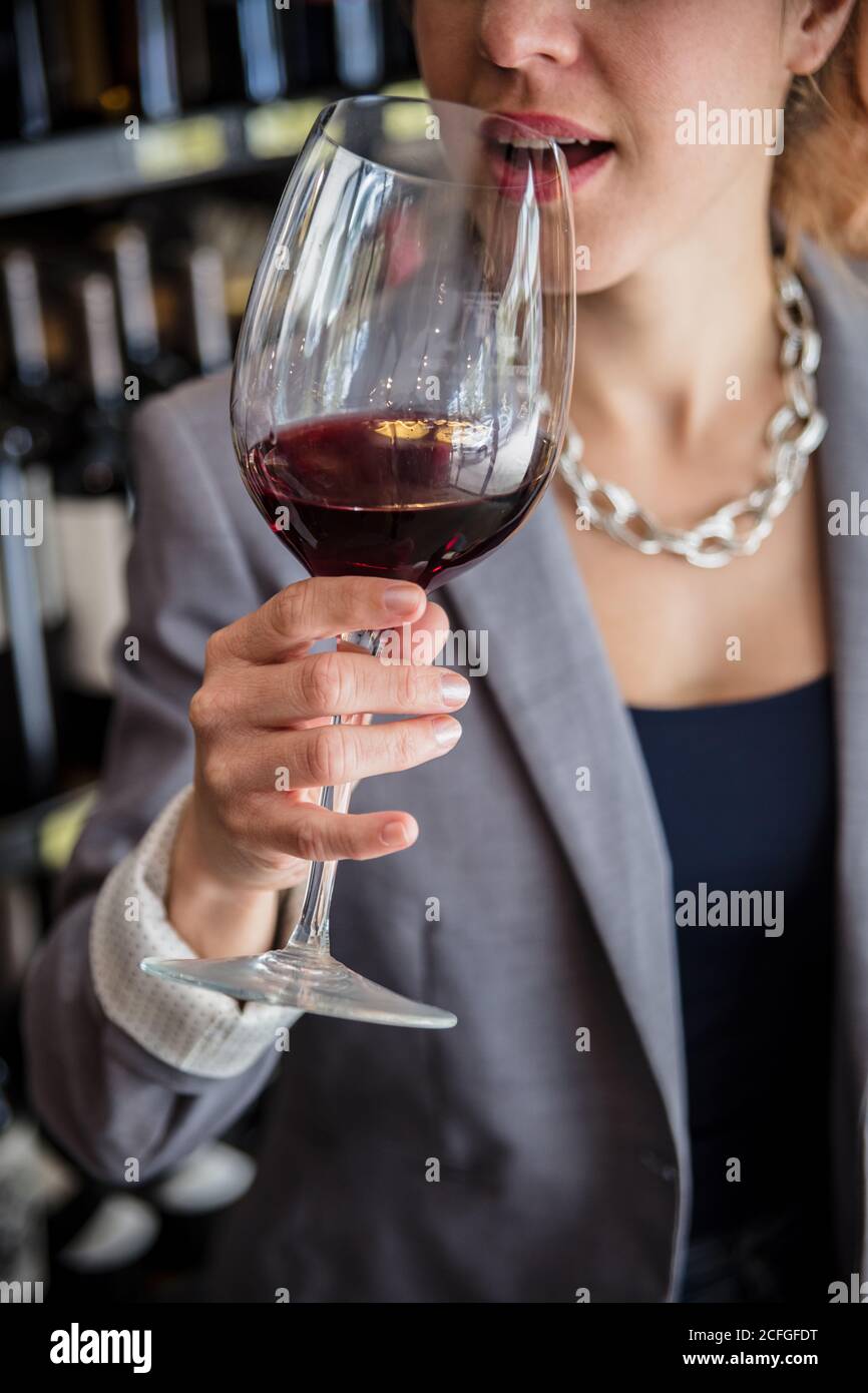 Ernte Aufnahme von eleganten Frau in Jacke Verkostung Rotwein und riecht es mit geschlossenen Augen in winehouse. Stockfoto