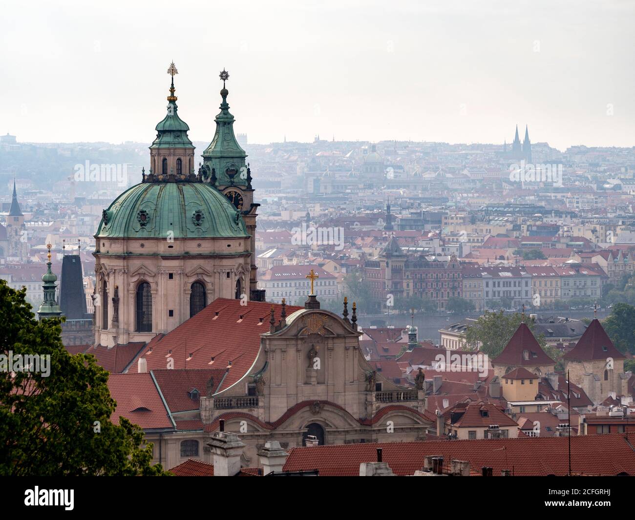 Prag von der Burg: Ein frühmorgens nebliger Überblick über die Stadt und ihre Türme vom Schlossgelände. Die Kuppel des St. Nikolaus dominiert den Vordergrund und die doppelten schwarzen Türme der St. Peter und Paul Basilika sind am Horizont. Stockfoto