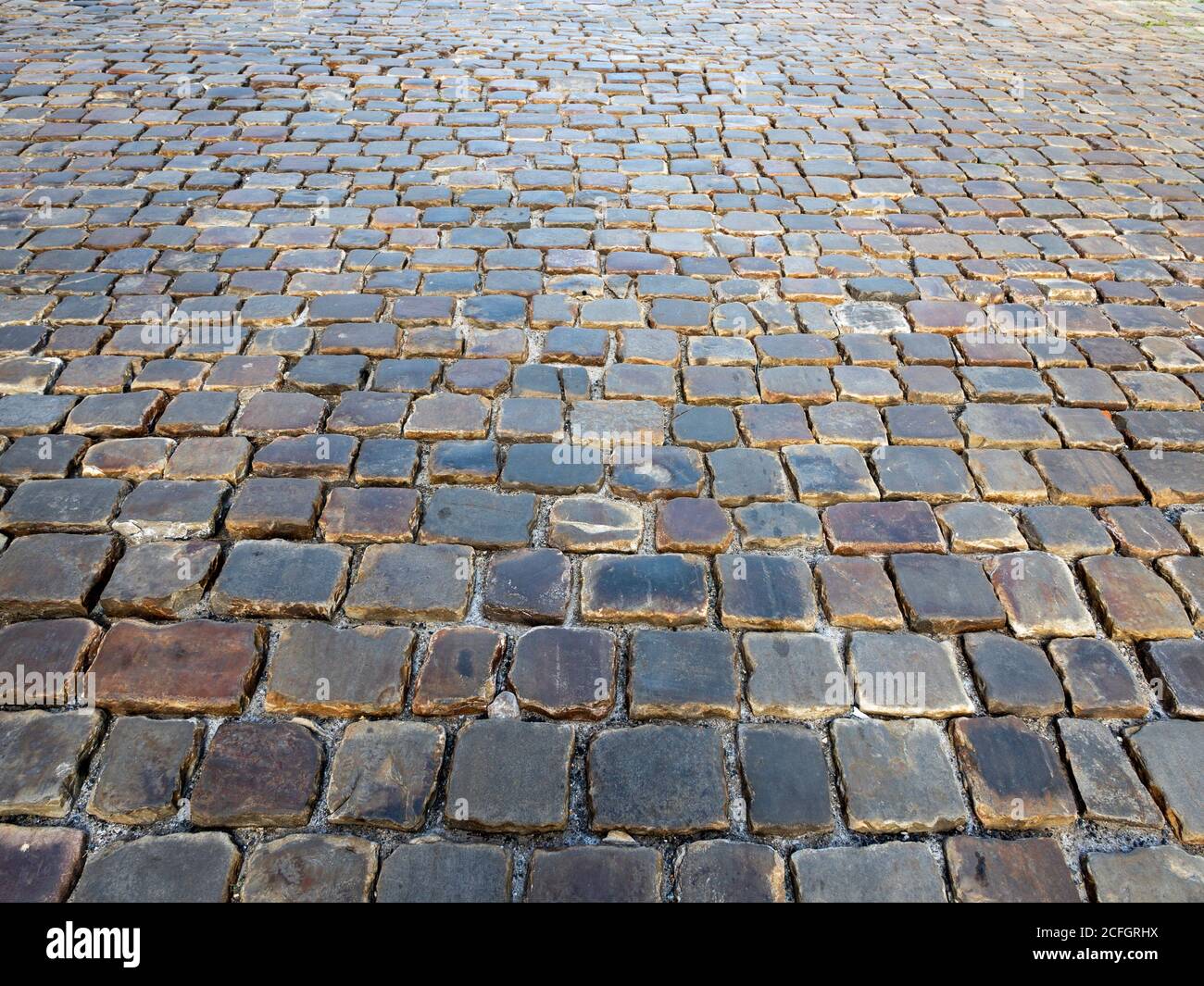 Abgenutzte Cobbles einer Prager Straße: Kopfsteinpflaster abgenutzte glatte und glänzende Pflaster eine breite Straße im Burgviertel von Prag. Stockfoto