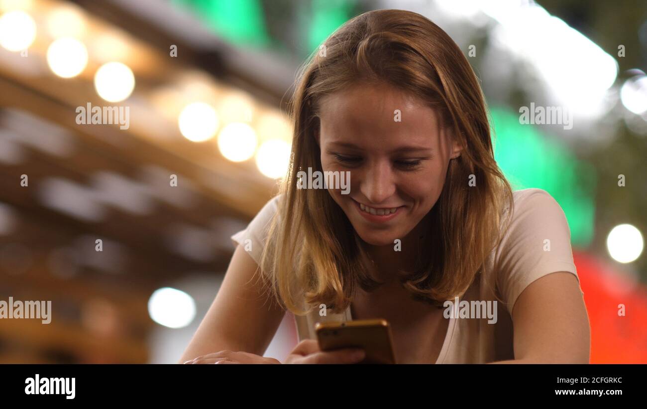 Fröhliche Frau an der Bar liest lustige Nachrichten über sie Mobil p Stockfoto