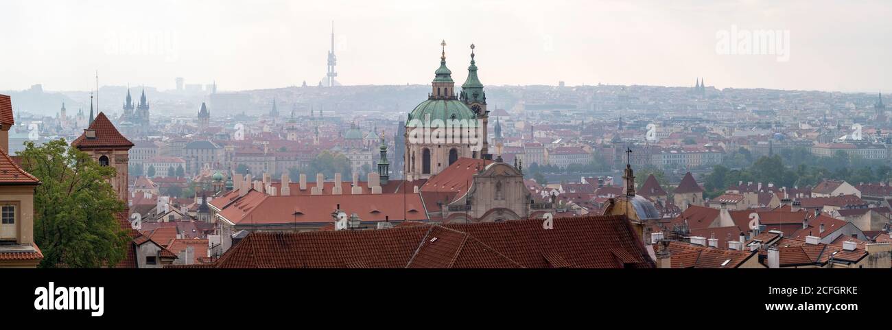 Prag von der Burg: Ein frühmorgens nebelhaftes Panorama auf die Stadt und ihre Türme vom Schlossgelände aus. Die Kuppel des St. Nikolaus dominiert den Vordergrund mit der Karlsbrücke im Mittelgrund und der Kirche von Peter und Paul und dem massiven Fernsehturm Žižkov am Horizont. Stockfoto