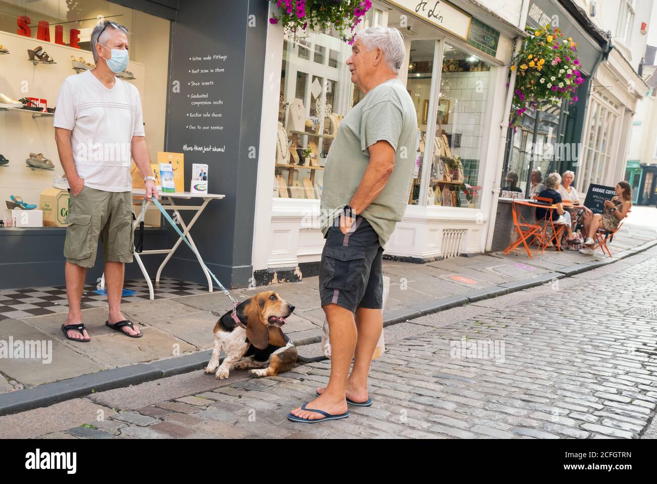 Canterbury, UK - 13. August 2020 ein Mann, der wegen Covid 19 eine Maske trägt und einen Basset Hund an der Leine hält, hat ein Gespräch, das auf einem Quai steht Stockfoto