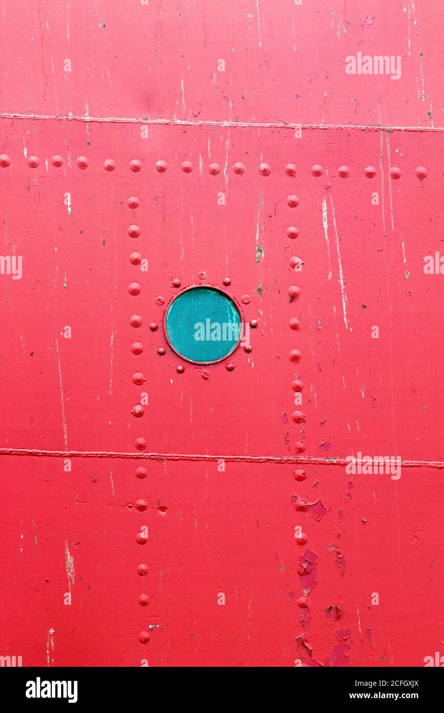 Rundes Hafenloch auf dem roten Rumpf eines Bootes in Harwich, Essex, Vereinigtes Königreich Stockfoto