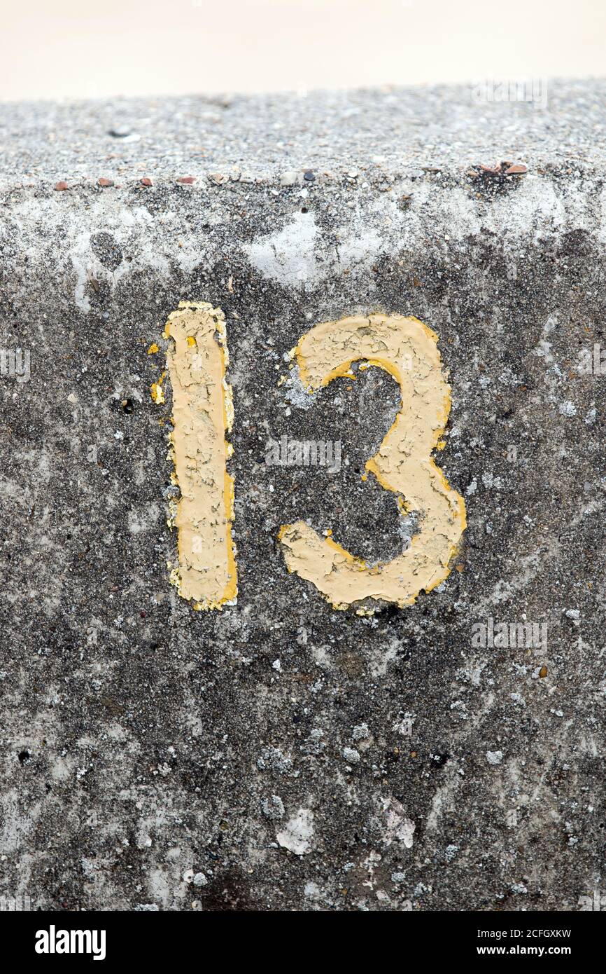 Nummer 13 in gelber Farbe i=auf einer Steinmauer in Harwich, Essex, Großbritannien Stockfoto