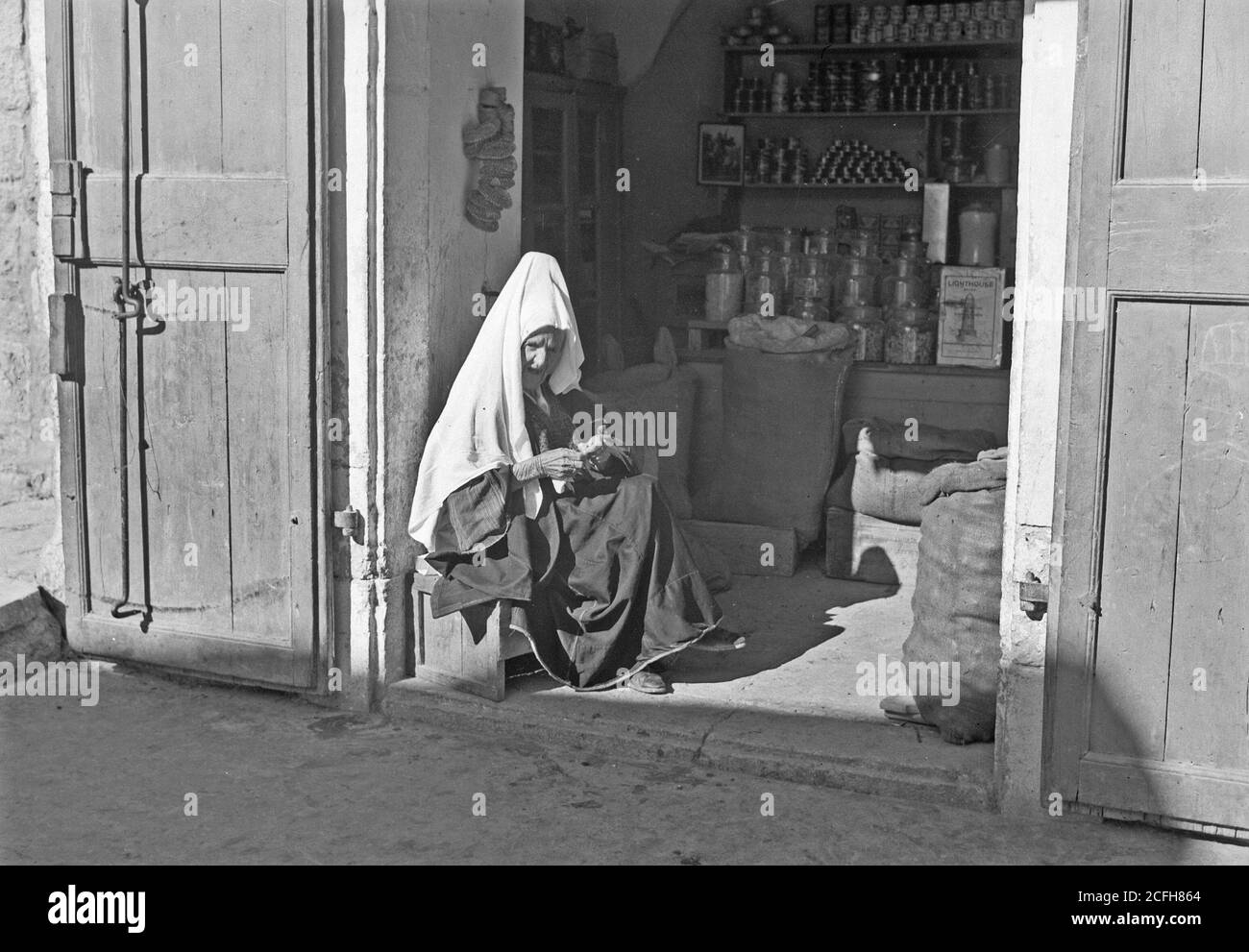 Bildunterschrift: Bethlehem Frau sitzt vor dem einheimischen Geschäft - Ort: Westbank--Bethlehem ca. 1934-1939 Stockfoto