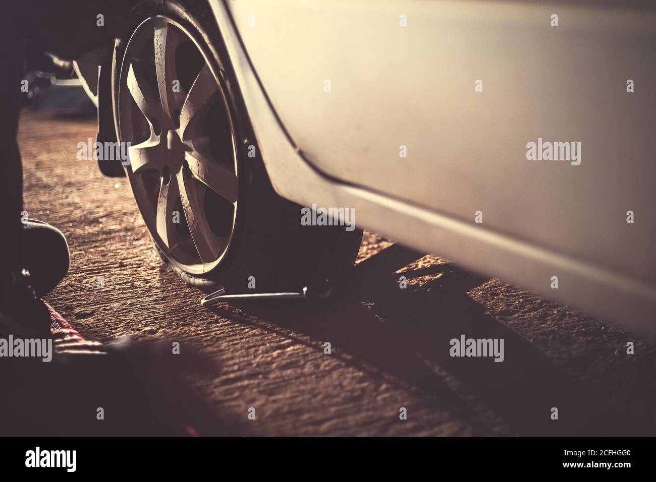 Flacher Autoreifen mit Reifenpflege, beschädigter Autoreifen bei Nacht. Stockfoto