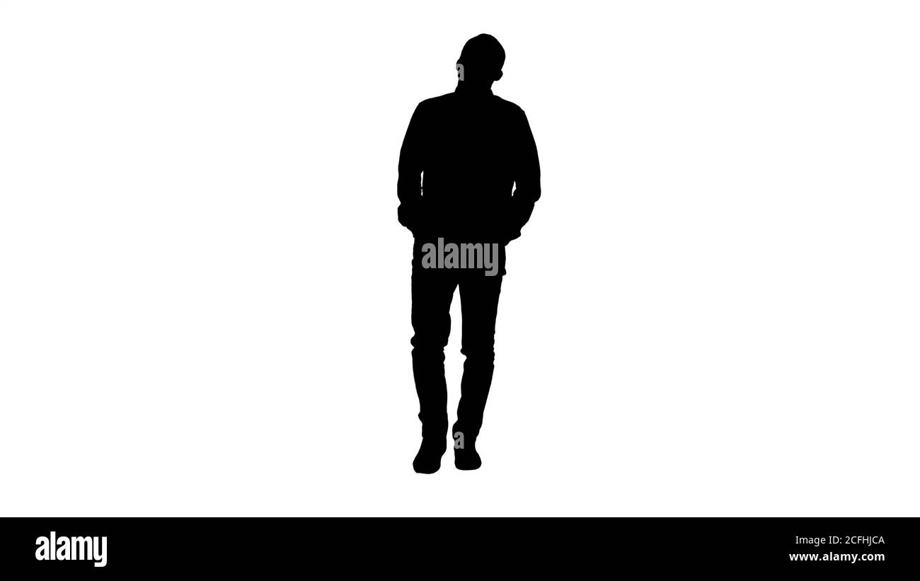 Silhouette junger Mann, der mit Händen in den Taschen und Pfeifen geht. Stockfoto