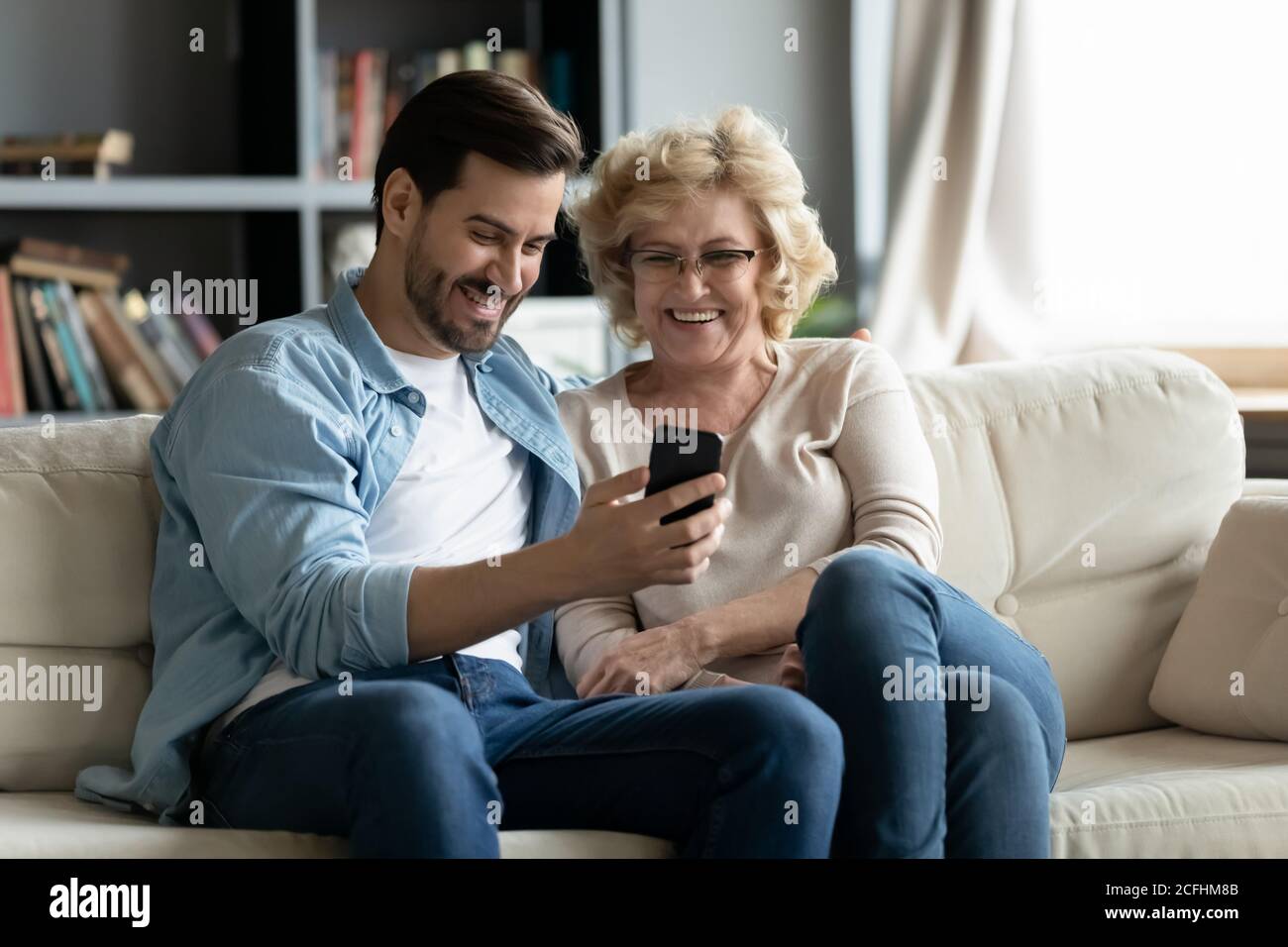 Überglücklich reife Frau und erwachsenen Sohn mit Smartphone zusammen Stockfoto