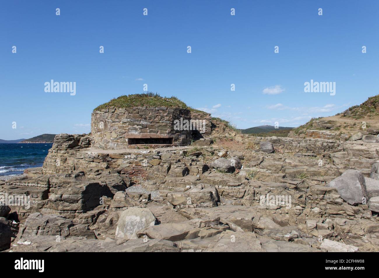 Maschinengewehr-Feuerstelle (DOT) aus der Zeit des Zweiten Weltkriegs, aus Wildstein und auf dem Boden verkleidet, am Kap Tobizin auf der russischen Insel in Stockfoto