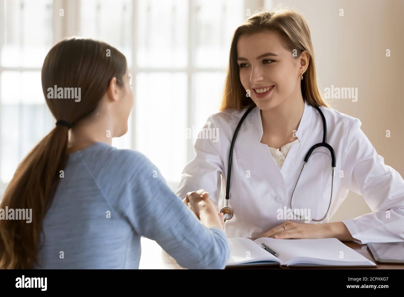 Lächelnde Ärztin schüttelt die Hand der Patientin beim Treffen Stockfoto