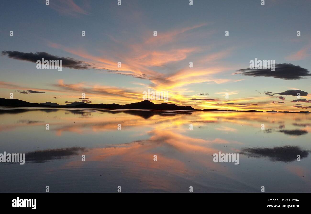 Spektakulärer Sonnenuntergang über dem See in den Anden, Bolivien. Orangefarbene Dämmerung, beeindruckende Wolkenlandschaft in Salar de Uyuni, Bolivien. Stockfoto