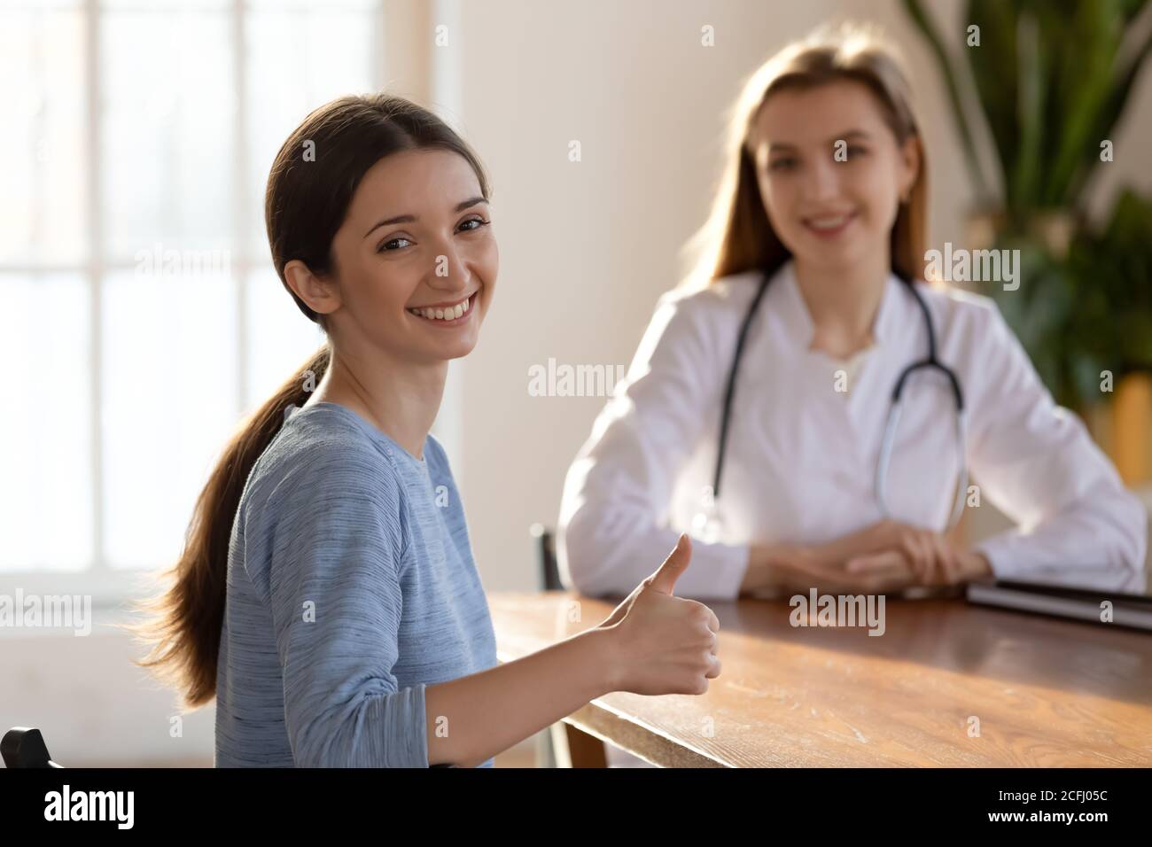 Lächelnder zufriedener Patient zeigt Daumen nach oben und empfiehlt medizinische Versorgung Stockfoto