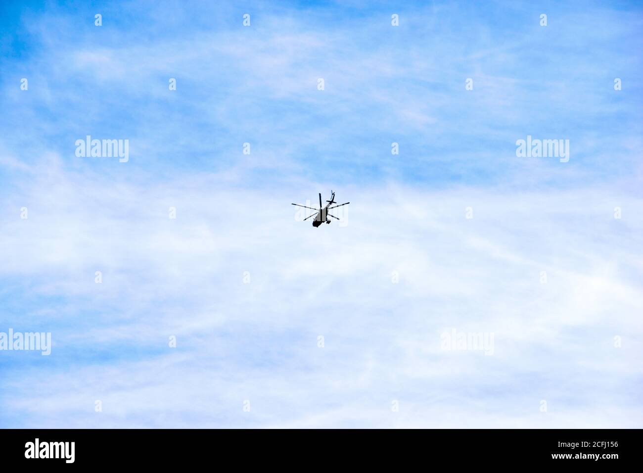 Der Hubschrauber fliegt gegen den blauen Himmel und Wolken Stockfoto