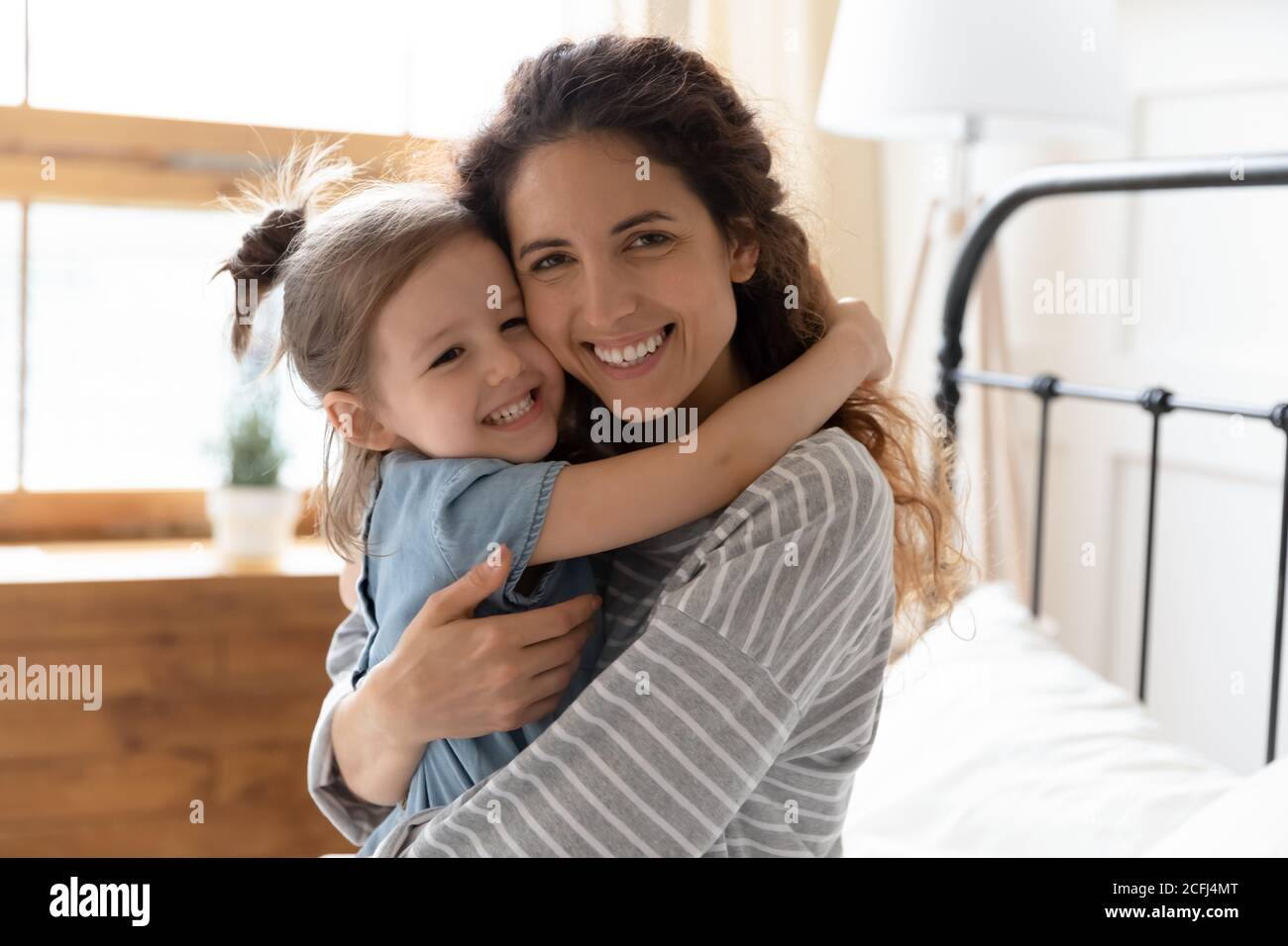 Portrait glücklich liebende Mutter kuschelt kleine Tochter beim Blick in die Kamera Stockfoto