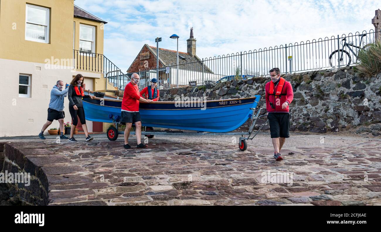 North Berwick, East Lothian, Schottland, Großbritannien, 6. September 2020. Antrittsreihe nach der Sperre: Mitglieder des NB Coastal Ruderclubs sind zum ersten Mal seit der Sperre im März aufgelegt. Covid-Safe-Maßnahmen sind vorhanden, einschließlich der Ruderer, die Gesichtsmasken tragen. Die Besatzung zieht den St. Ayles-Schiff mit einem Anhänger aus dem Hafen Stockfoto