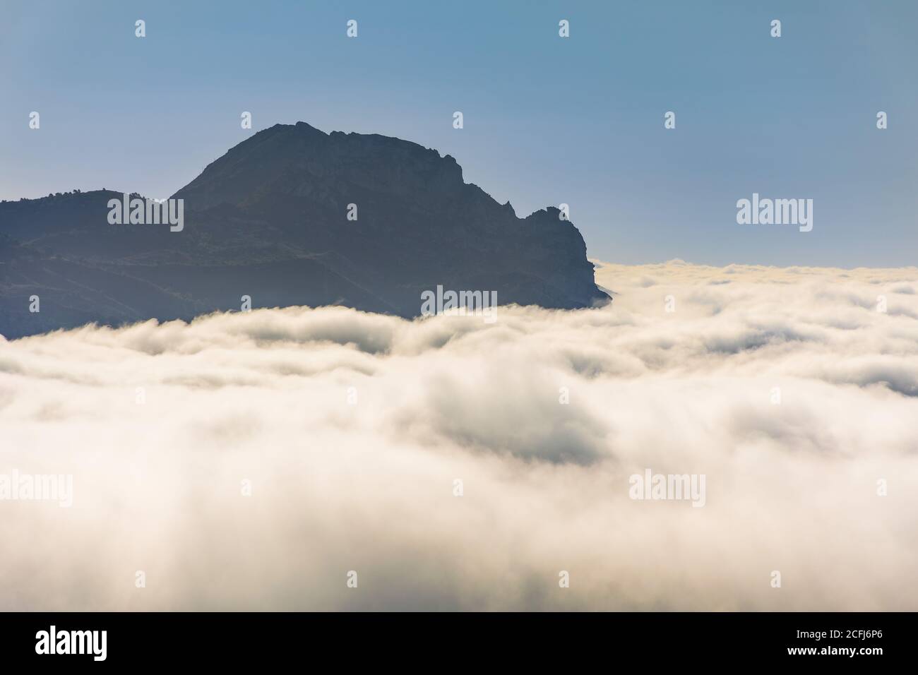 Blick auf einen Berggipfel, der über einem Wolkenmeer thront. Stockfoto