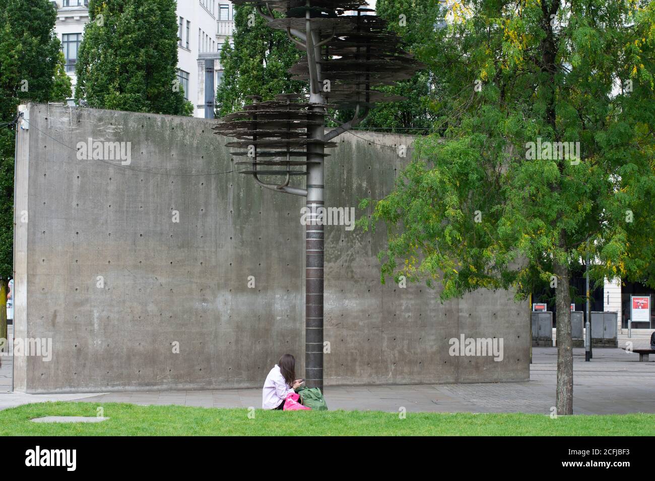 Busbahnhof Manchester Piccadilly. Der minimalistische japanische Architekt Tadao Ando entwarf in Picadilly Gardens eine geschwungene Betonwand mit einer Frau, die an der Basis saß. Stockfoto