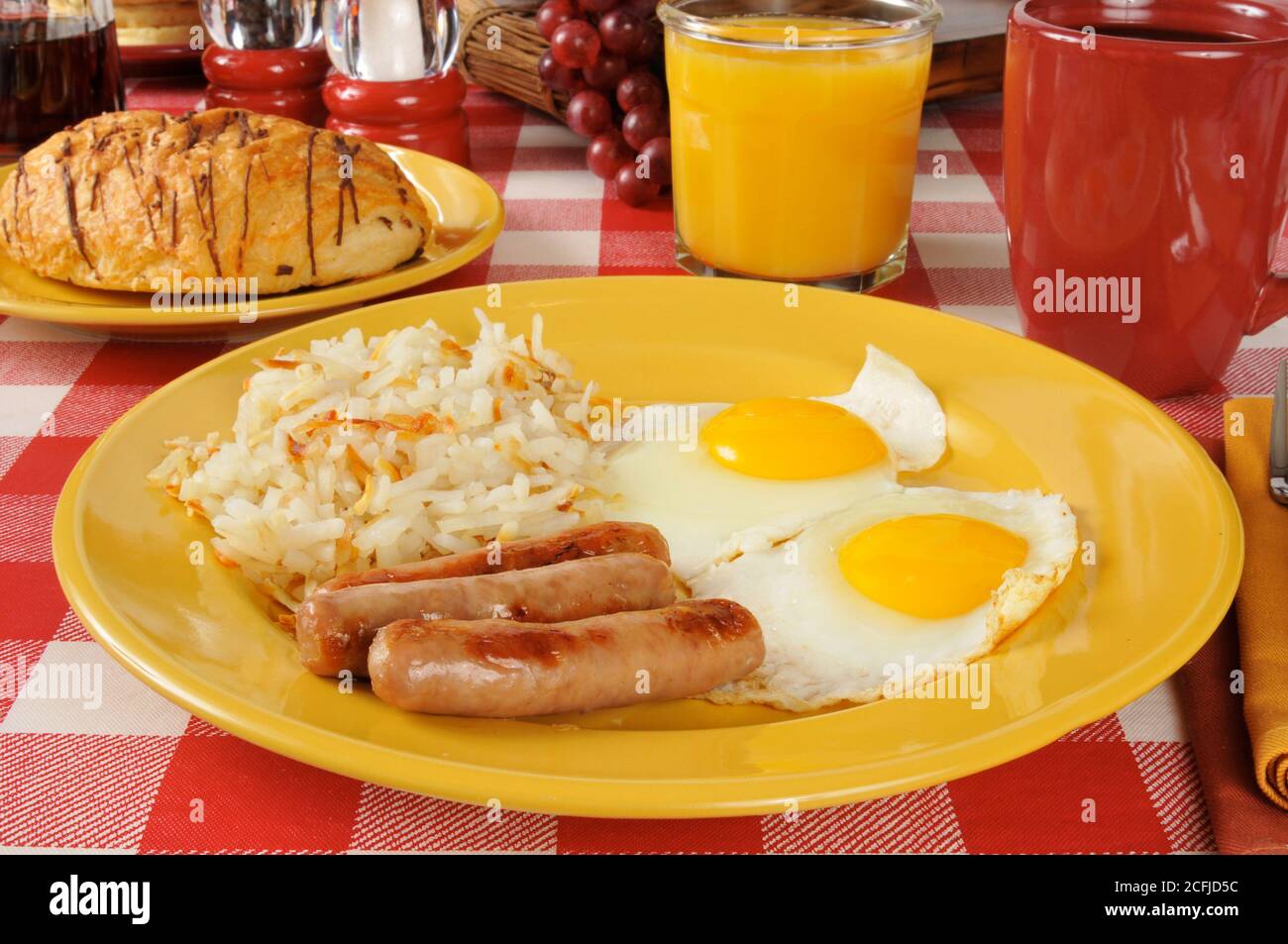 Wurst- und Eierfrühstück mit Kartoffelrösti und Schokolade Gefüllte Croissants Stockfoto
