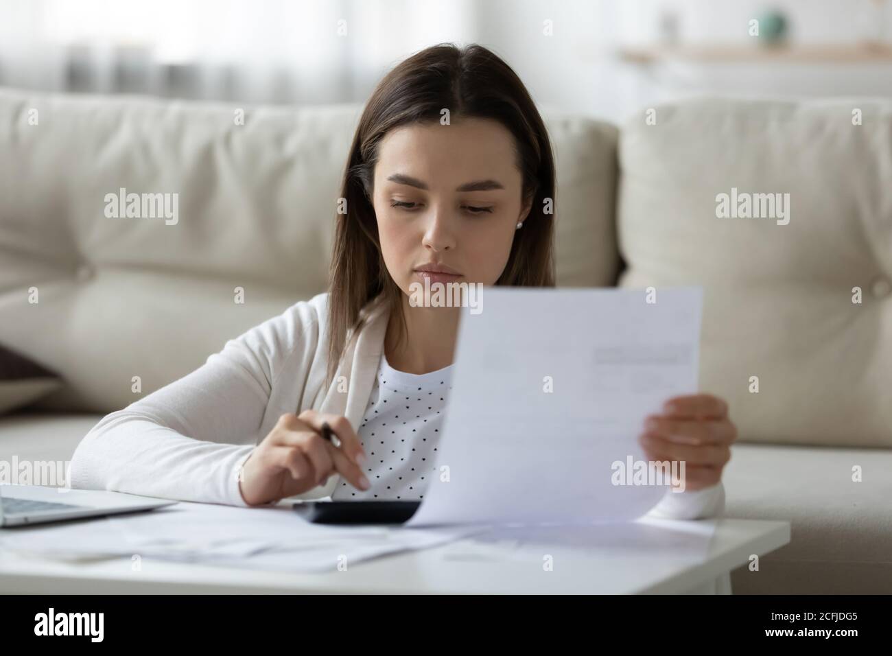 Seriöse Frau allein zu Hause Haushaltsbudget berechnen. Stockfoto