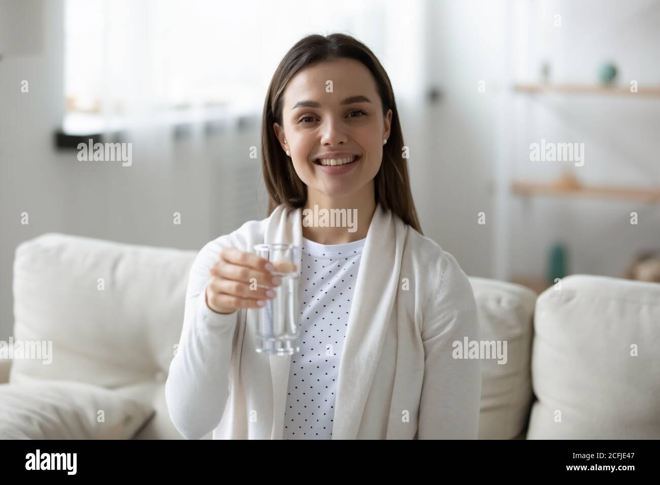 Porträt einer glücklichen jungen Frau, die ein Glas reines Wasser hält. Stockfoto