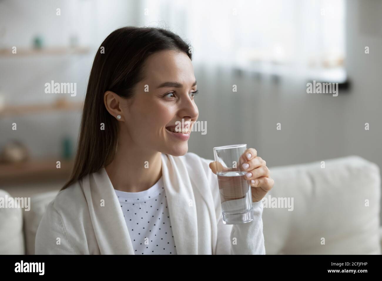 Lächelnd hübsches junges Mädchen, das Glas reines Süßwasser hält. Stockfoto
