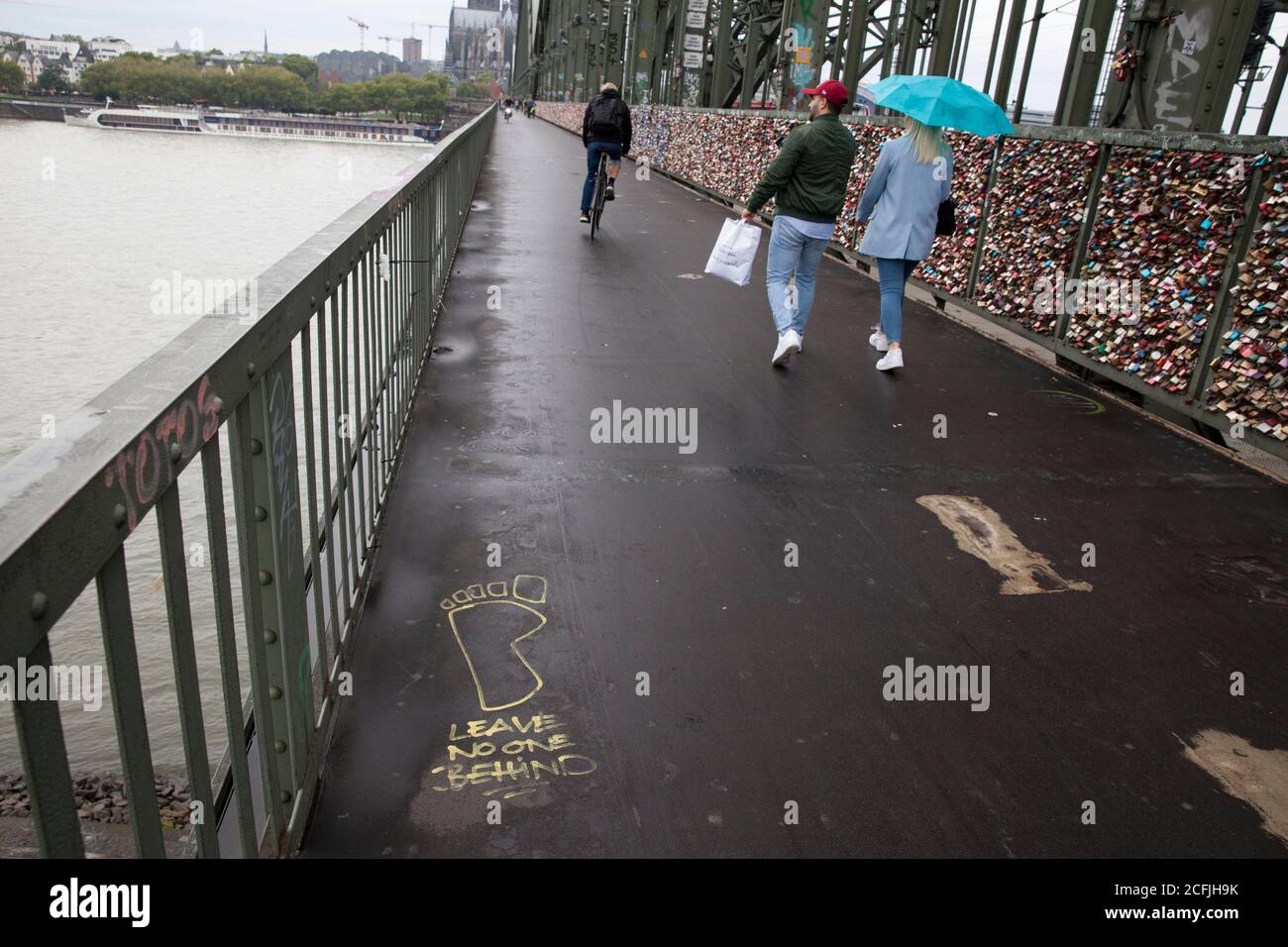 Graffiti 'Leave no one behind' auf der Hohenzollernbrücke, Blick auf den Dom, Köln, Deutschland. Graffiti 'Leave no one behind' auf der Stockfoto