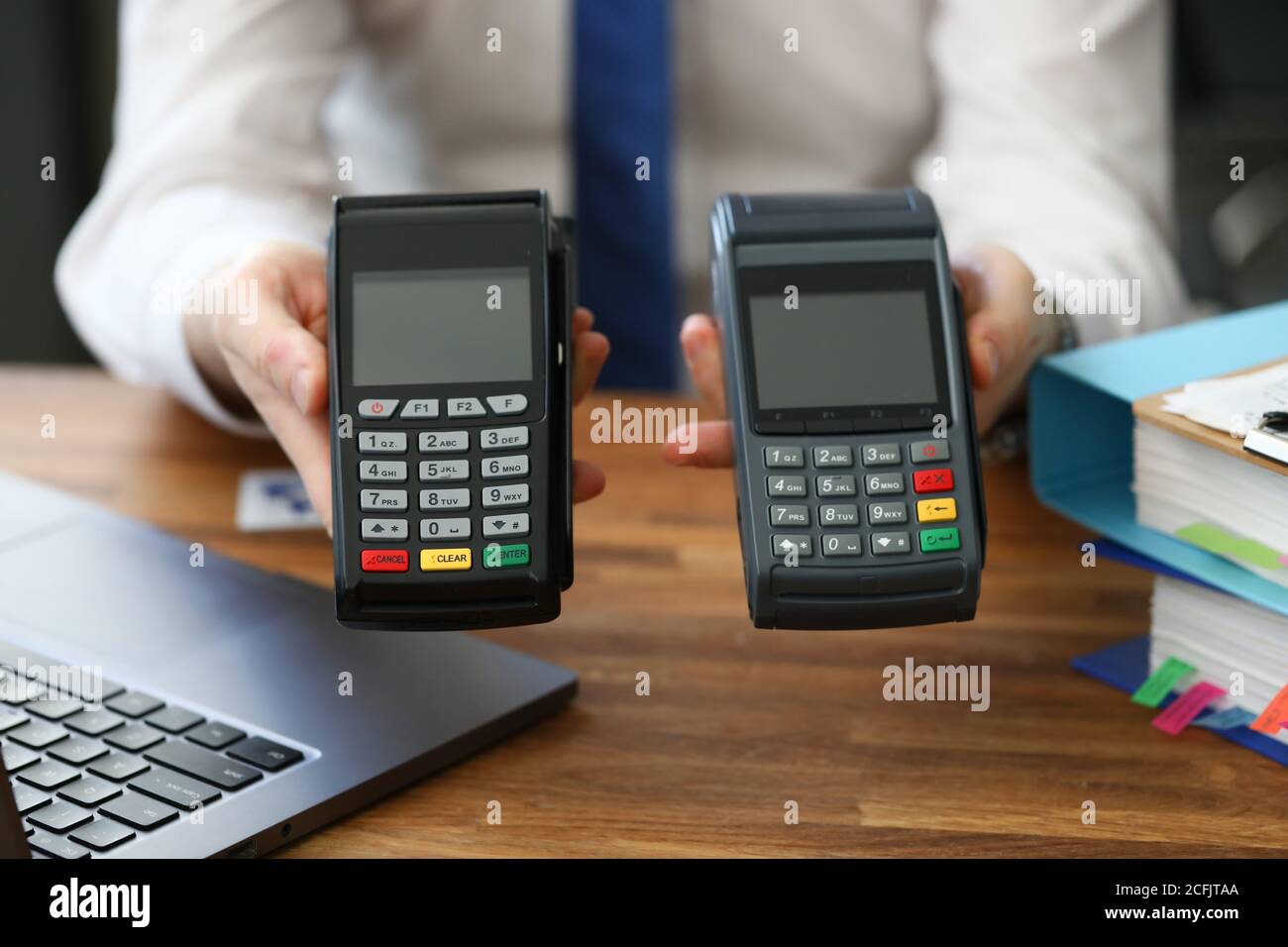 Männliche Hände im Büro halten zwei Zahlungsterminal Stockfoto