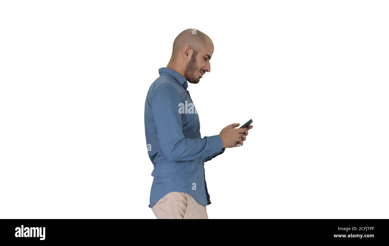 Junger Mann, der läuft und ein Telefon auf weißem Hintergrund benutzt. Stockfoto