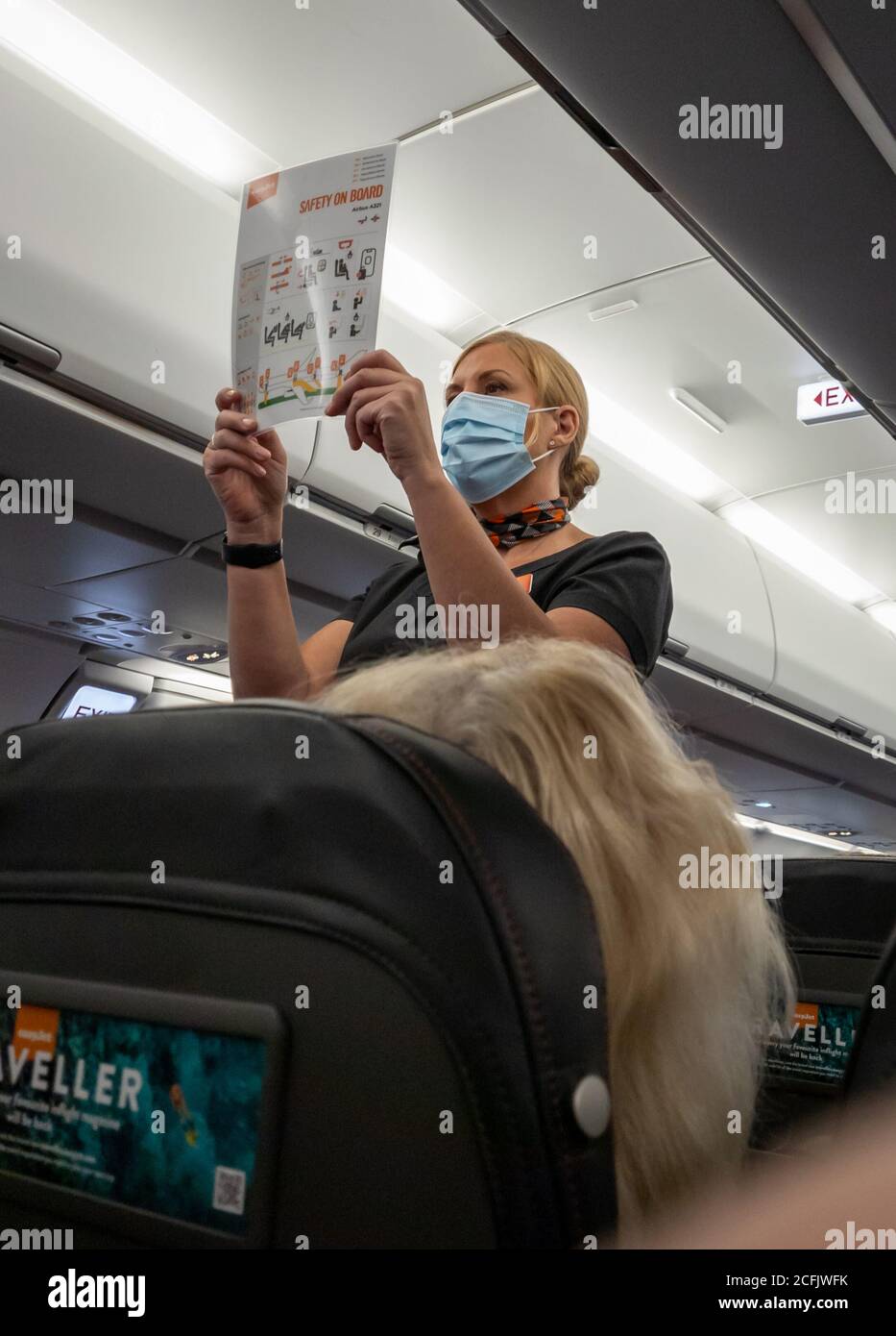 Eine Flugbegleiterin mit Gesichtsmaske/-Abdeckung, die die Flugsicherheitsdemostration an Bord eines easyJet-Fluges macht. Stockfoto
