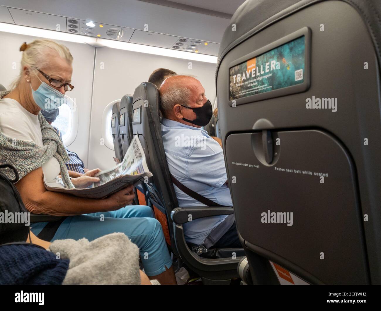 Passagiere mit Gesichtsmaske/-Abdeckung an Bord eines easyJet-Fluges. Stockfoto