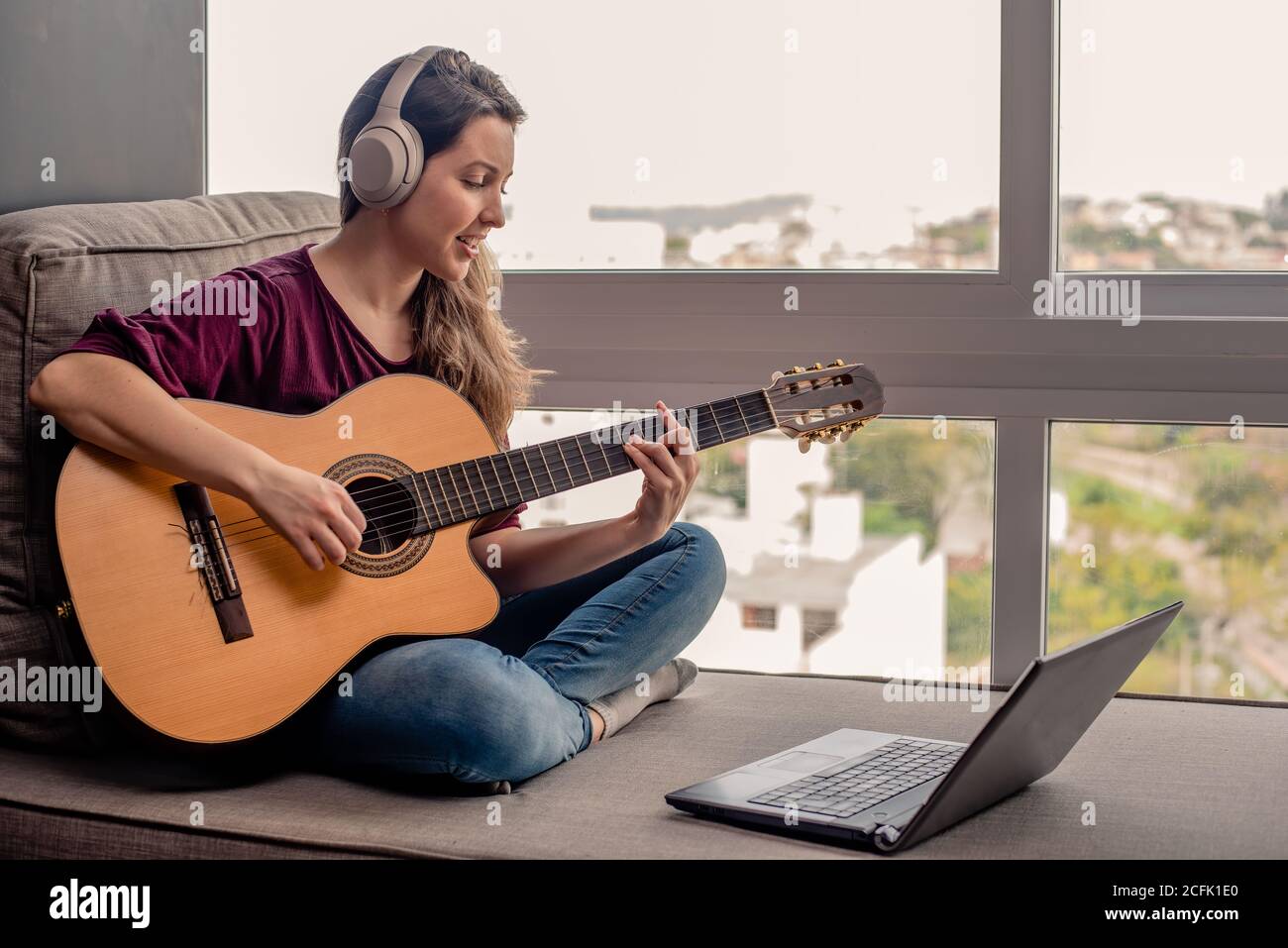 Frau online lernen, wie man Gitarre spielen Stockfoto