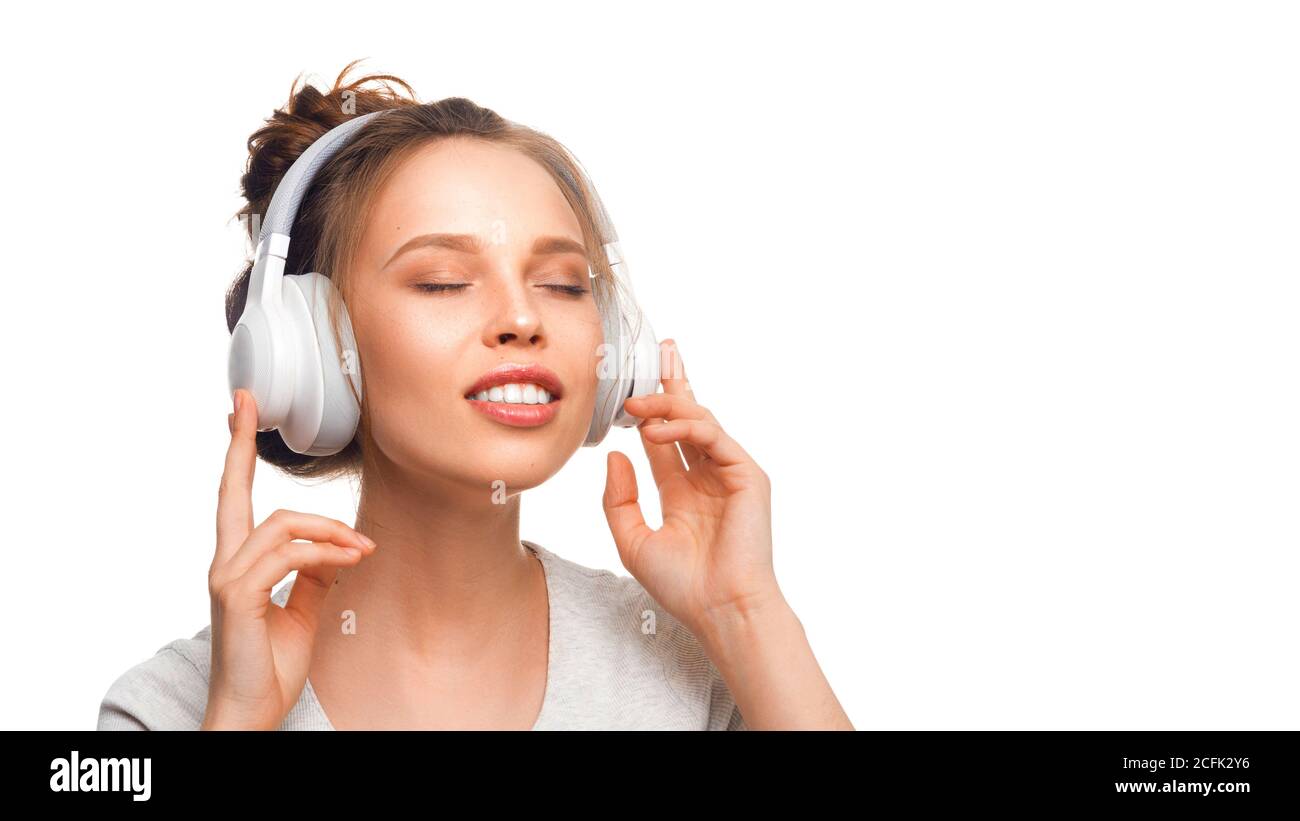 Attraktive Mädchen mit geschlossenen Augen hören die Musik über Kopfhörer auf weißem Hintergrund. Sound Groove mit geschlossenen Augen. Nahaufnahme Stockfoto