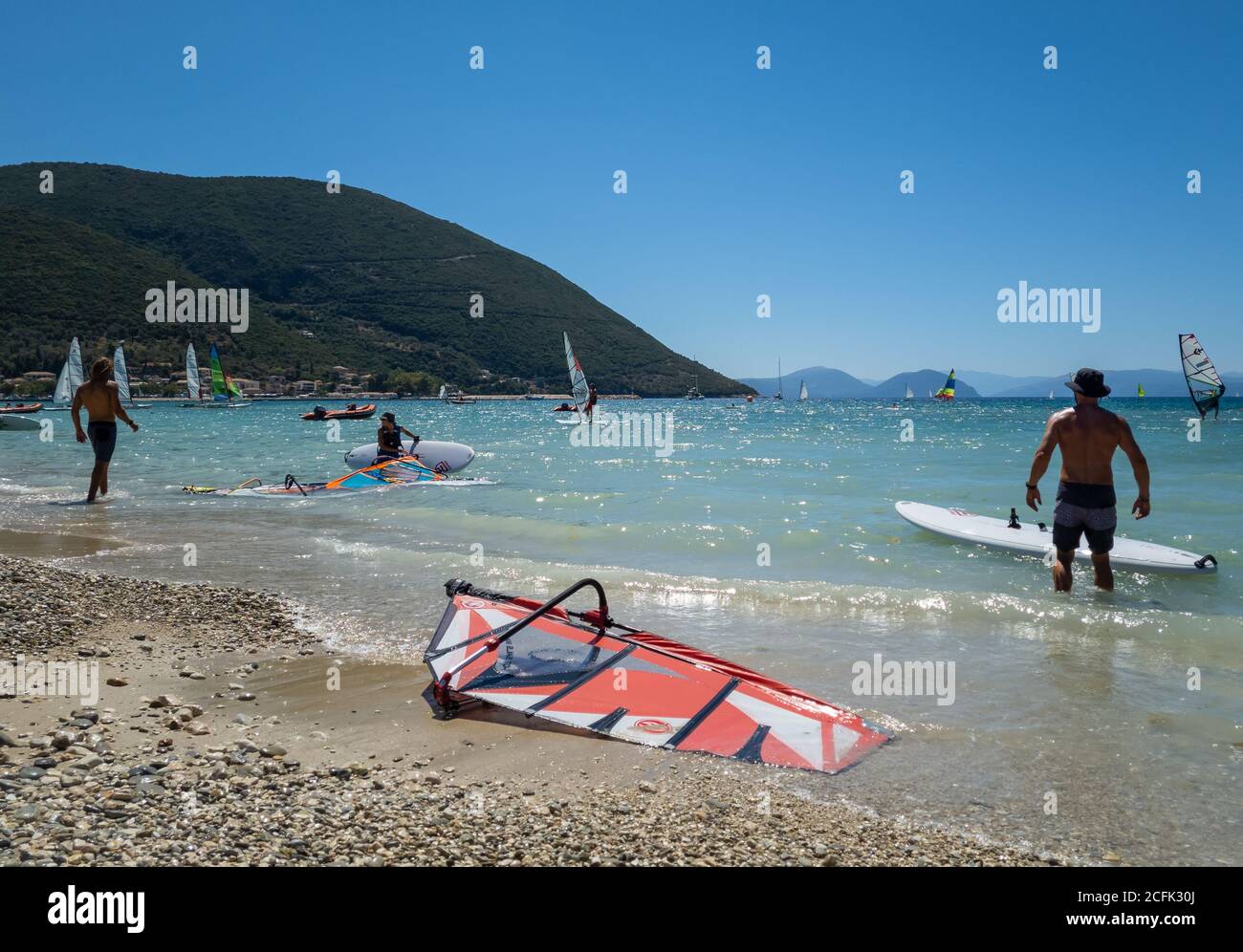 Touristen genießen den Sport zum Windsurfen in den flachen Gewässern der Bucht Vasiliki. Stockfoto