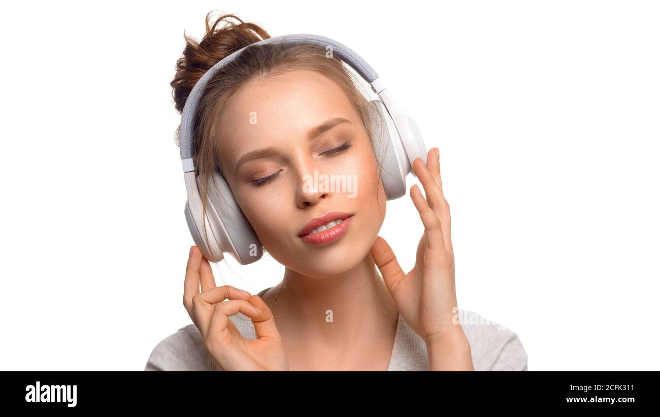 Attraktive Mädchen mit geschlossenen Augen hören die Musik über Kopfhörer auf weißem Hintergrund. Stockfoto