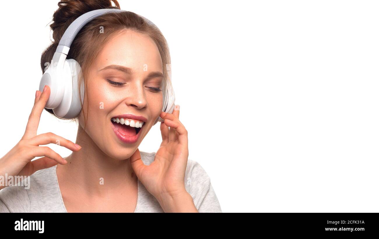 Attraktive Mädchen singen mit Kopfhörern auf weißem Hintergrund. Stockfoto