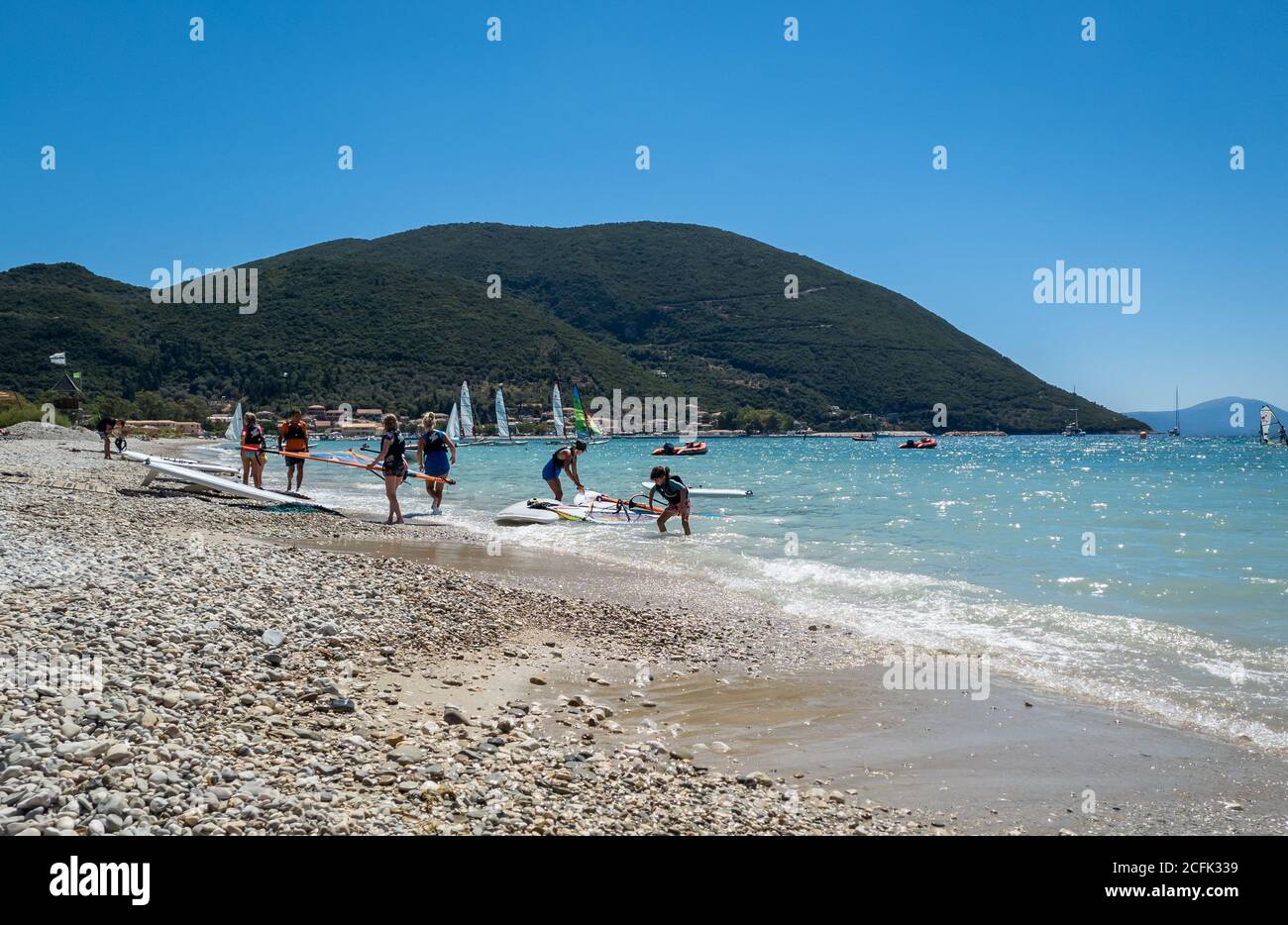 Touristen genießen den Sport zum Windsurfen in den flachen Gewässern der Bucht Vasiliki. Stockfoto